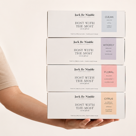 Four stacked white product boxes labeled Jack Be Nimble, each with a different colored flavor block (blue, lavender, pink, peach), held in a person's hands against a warm off-white background.